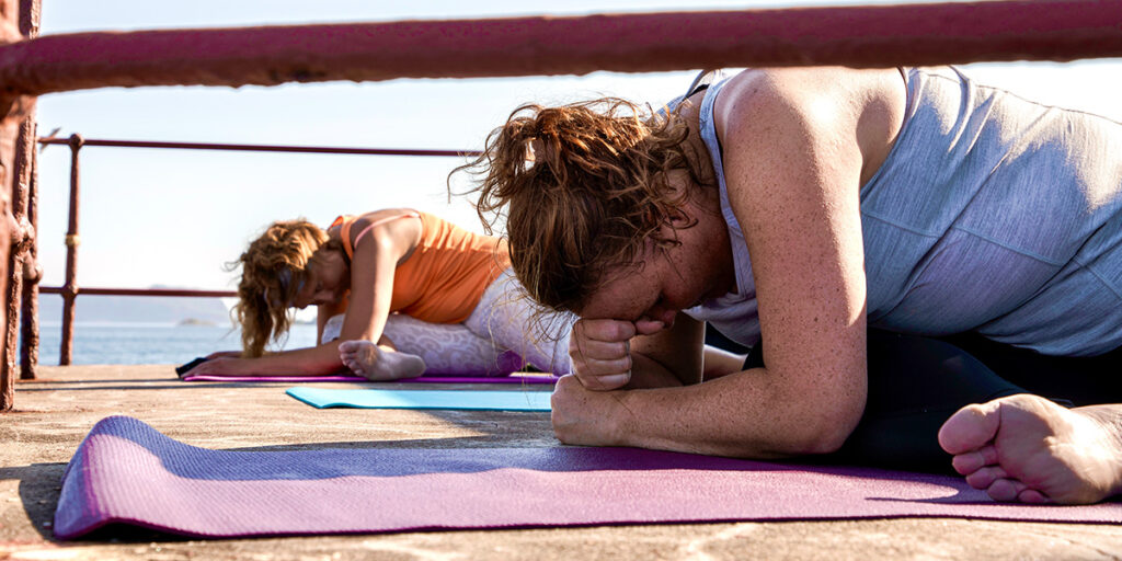To damer gjør yoga på Stabben fyr. Foto.